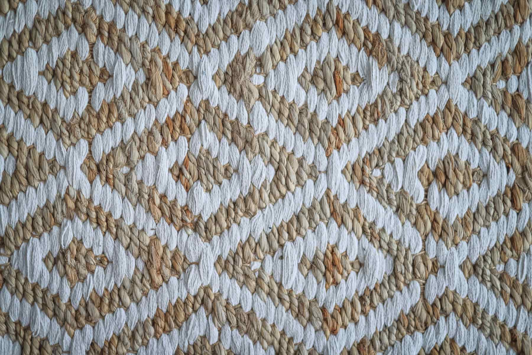 Close detail of a natural fiber rug weave beside a wool pile rug